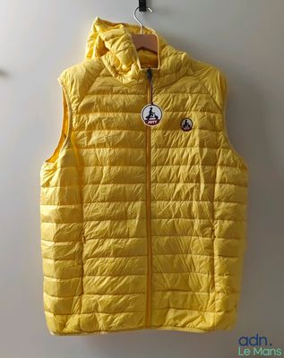 the yellow vest is hanging on the wall by a hanger
