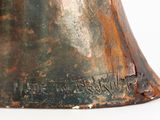 a bronze bell that is sitting on a white surface
