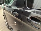 a close up of a car door handle with a bus in the background
