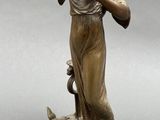 bronze statue of a woman drinking from a pitcher on a marble base