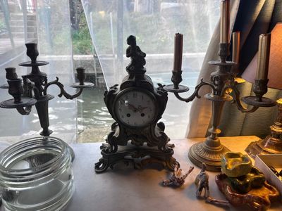 a table with a clock and candles on it next to a window