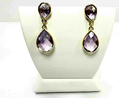 une paire de boucles d'oreilles en améthorate et diamants exposée sur un mannequin blanc
