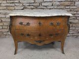 une commode au plateau en marbre devant un mur de briques