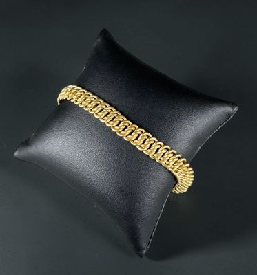 a gold chain bracelet on a pillow on a black background
