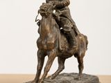 bronze statue of a man riding a horse on a wooden table