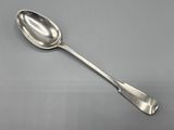 cuillère en argent à long manche posée sur une surface grise