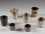 six coupes en argent sont disposées en cercle sur une surface blanche