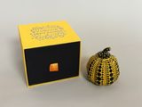 a small yellow pumpkin sitting next to a black box