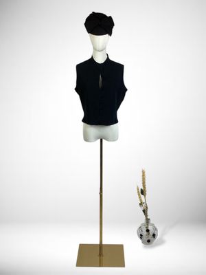 mannequin with black shirt and hat on stand next to a vase