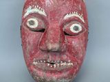 une image représentant un masque rouge avec un visage blanc sur fond gris