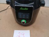 une photo d'un autocuiseur électrique noir posé sur une boîte en carton