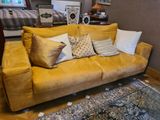 un canapé jaune recouvert de nombreux coussins dans un salon