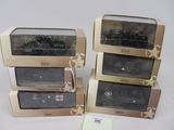 trois boîtes contenant des trains miniatures posées sur une surface blanche