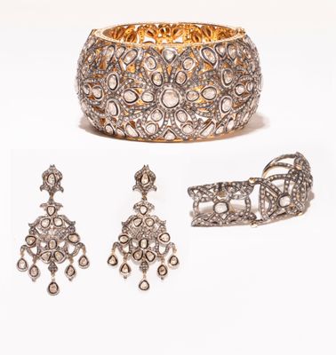 un gros plan d'un bracelet, d'une bague et d'une boucle d'oreille sur fond blanc