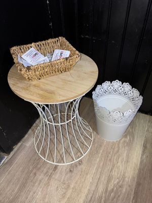 une petite table sur laquelle se trouve un panier, à côté d'une poubelle