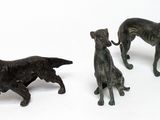 three figurines of dogs standing next to each other on a white surface