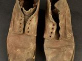 an old pair of brown boots with holes in them on a black surface