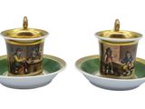 two cups and saucers with pictures of people on them
