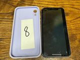 two cell phones are sitting on a wooden table with a note taped to the back of them