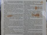 un vieux journal posé sur une table, à côté d'un verre de vin