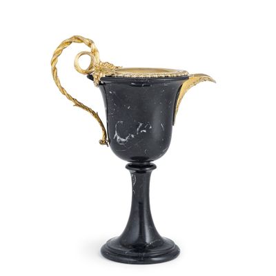 une coupe ancienne noire et dorée, munie d'anses et posée sur un socle