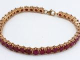 a close up of a bracelet with red stones on a white surface