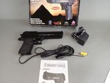 a desert eagle gun with a box and charger on the table