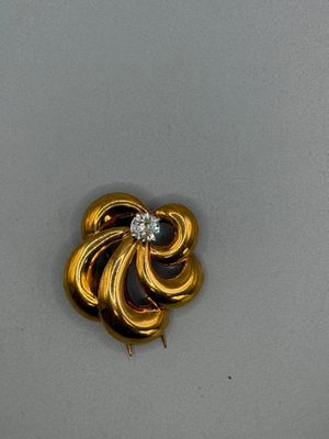 an image of a gold brooch with a diamond in the center
