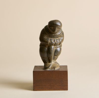 une petite statue représentant un homme en combinaison spatiale, posée sur un socle en bois