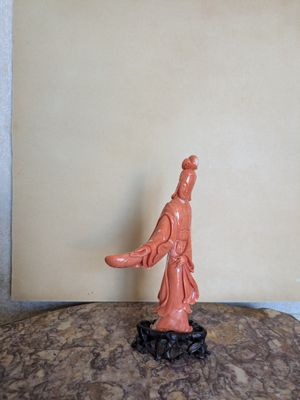 une figurine représentant une femme debout au sommet d'un rocher