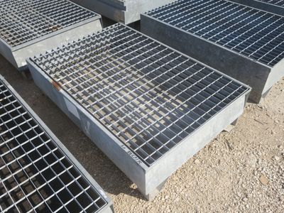 plusieurs grilles en acier sont empilées les unes sur les autres au sol