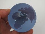 a person holding a small blue globe in their hand
