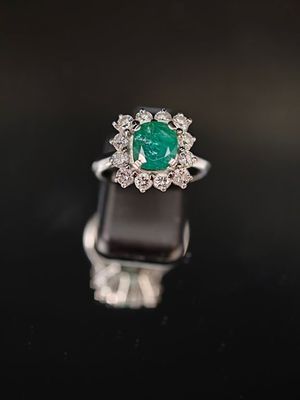 une bague en émeraude et diamant sur une surface noire
