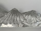 une sculpture métallique représentant une montagne avec, en arrière-plan, un sommet enneigé