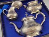 three silver teapots in a blue box on a table