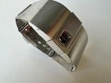 silver metal bracelet with a black button on a white surface