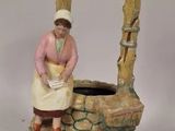 une figurine représentant une femme debout près d'un puits