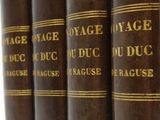 five antique books are lined up on a shelf in a row