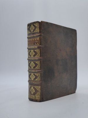 un vieux livre à la couverture brune posé sur une surface blanche
