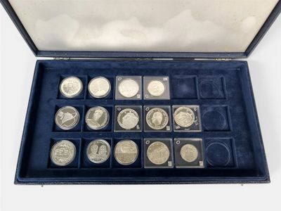 an assortment of silver coins in a blue case on a white surface