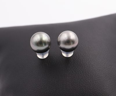 a pair of pearl earrings on a black leather surface