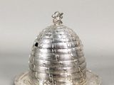 a silver plate with a dome on top of it on a gray surface