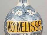 un vase bleu et blanc sur lequel est collée une étiquette jaune