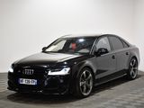 L'Audi noire est garée dans une grande pièce au sol carrelé.