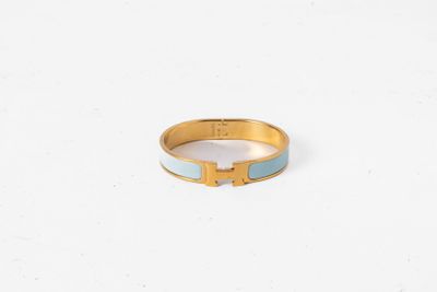 une bague dorée et bleue sur laquelle figure la lettre « h »