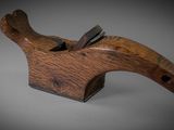 an old wooden plane with a wooden handle on a gray surface