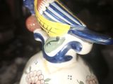 a blue and yellow bird sitting on top of a bell