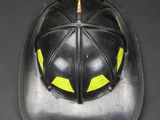 an old fireman ' s helmet with yellow eyes on a black background