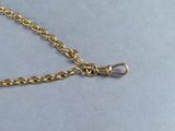 a close up of a gold chain with a clasp on a gray surface