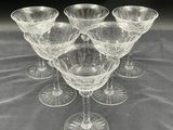 six clear wine glasses sitting on a table with a black background